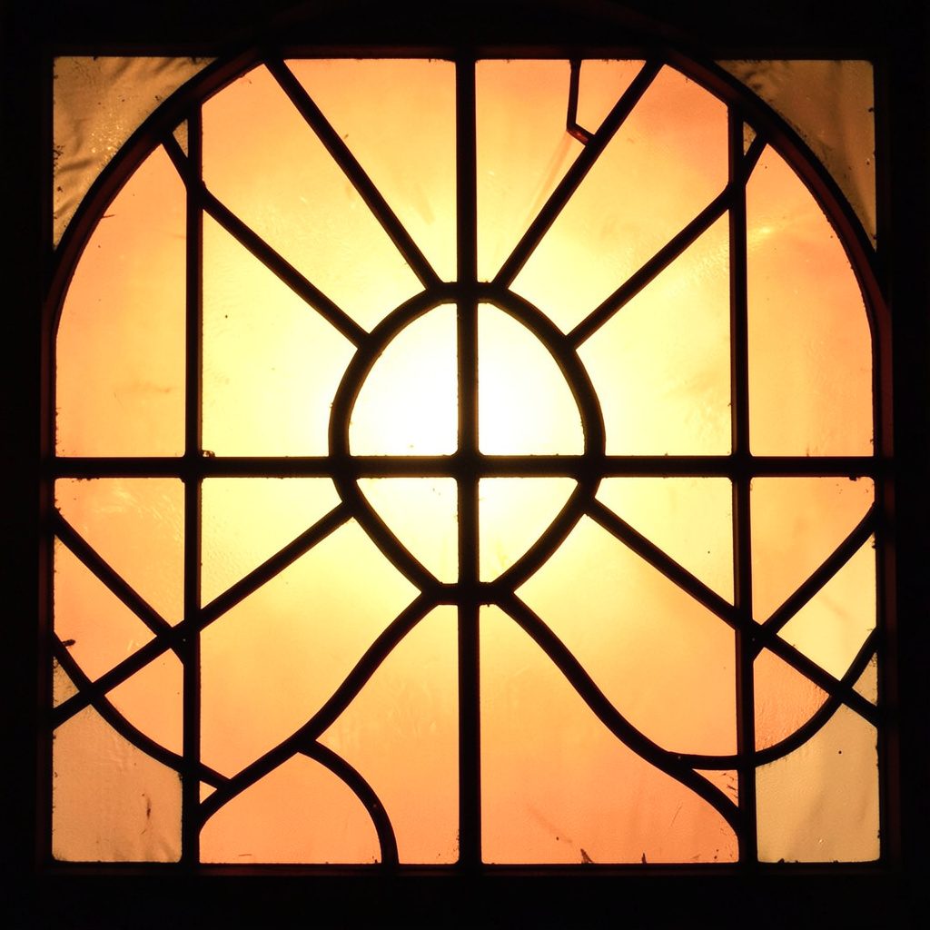 A stained-glass style composition with bold leaded lines separating panels of leafy green, soft blush, and warm amber, evoking thoughtful contemplation.